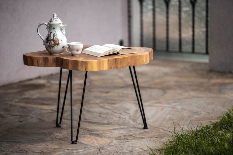 Fertiger Holztisch mit Kaffee und Buch auf einer Terrasse